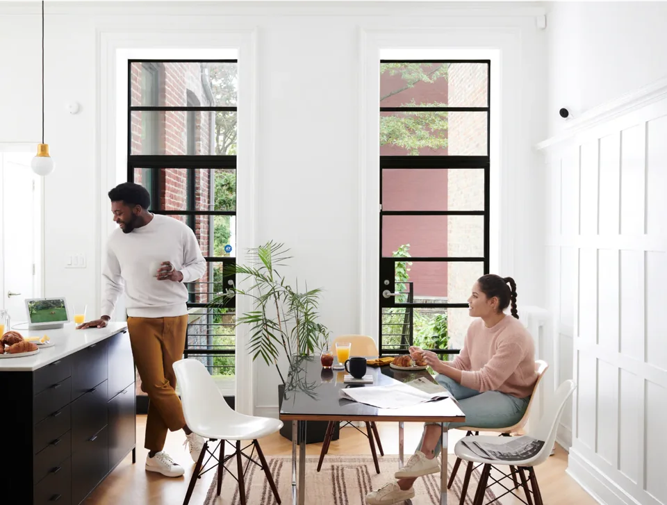 Homeowners in a bright kitchen with smart home security devices