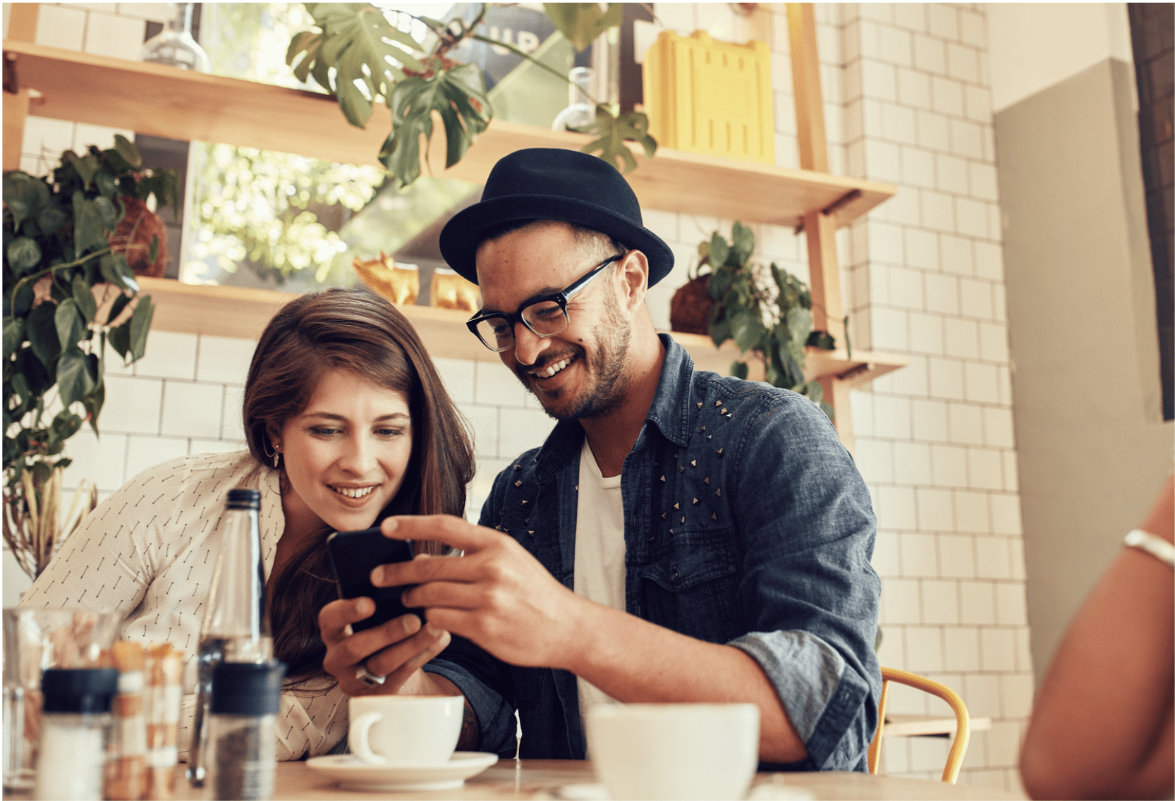 Couple using a mobile phone while seated in a cafe