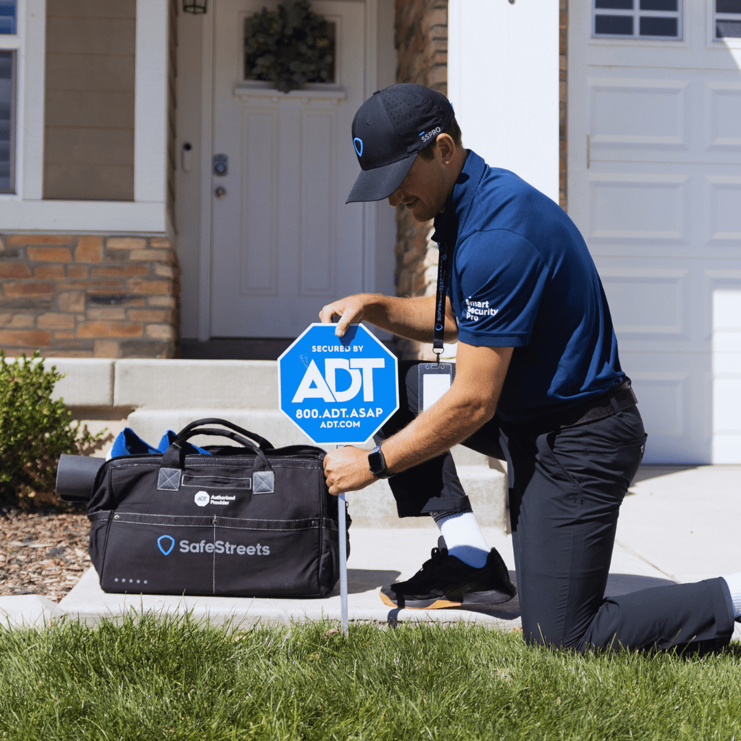 Professional installer placing ADT yard sign at a home